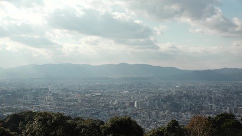 KYOTO, JAPAN - DEC 2021 : Aerial panoramic view of Kyoto city in daytime. Scenery of mountain, streets and buildings around downtown area. Japanese nature and traditional old town concept video.