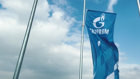Cacak, Serbia - March 10, 2022: Gazprom flag waving in wind on gas station in Serbia. Gazprom is multinational energy corporation headquartered in Saint Petersburg, Russia