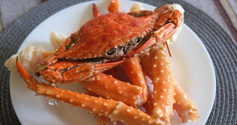 boiled crabs on a white plate. red and white crab claws and legs. floating crab lies on the legs of a king crab