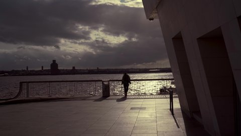 LIVERPOOL, UK - 2022: The silhouette of a man overlooking Liverpool Albert Dock in dark sunset weather
