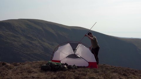 WALES, UK - 2022: An explorer erecting a tent to wild camp in the mountains of Snowdonia in Wales