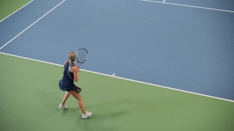 Female Tennis Player Servers by Hitting Ball with a Racquet During Championship Match. Professional Woman Athlete Strikes Successfully. World Sports Tournament. Slow Motion High Angle Wide Shot