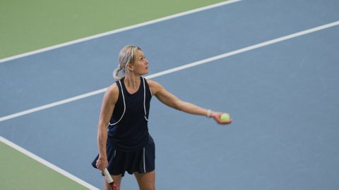 Female Tennis Player Servers by Hitting Ball with a Racquet During Championship Match. Professional Woman Athlete Strikes Successfully. World Sports Tournament. Slow Motion High Angle Medium Shot