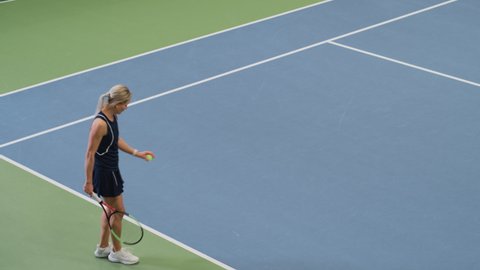 Female Tennis Player Servers by Hitting Ball with a Racquet During Championship Match. Professional Woman Athlete Strikes Successfully. World Sports Tournament. Static High Angle Wide Shot