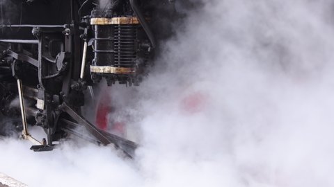 Vintage steam train locomotive. Pair locomotive train leaking smoke, steam ignited from behind. Antiquarian black steam engine. Old vintage train on the railroad. Close-up