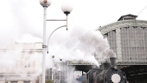 Vintage steam train locomotive, locomotive wheels. High quality. Steam train departs from railway station. Old vintage steam train on the rail road. Smoke covering