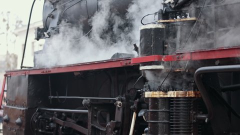 Vintage steam train locomotive. Pair locomotive train leaking smoke, steam ignited from behind. Antiquarian black steam engine. Old vintage train on the railroad. Close-up