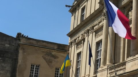 The Ukraine flag and European flag with France flag at the window waving united in support of the invasion of Ukraine and its joining the European Union. Europeans support Ukraine joining the EU.