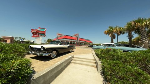 Gulf Shores, AL, USA - May 2, 2022: Famous Sunliner Diner Gulf Shores Beach Alabama USA. 4k approach between two classic cars gimbal stabilized