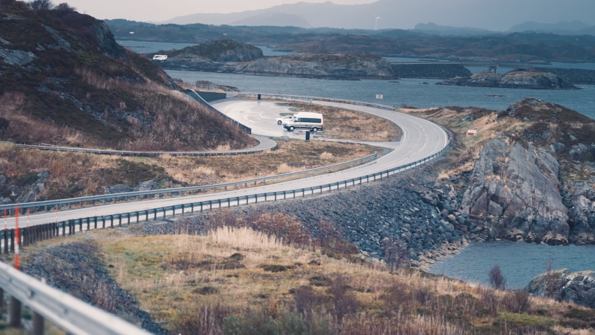 Lyngholmen parking on the Atlantic road. Campers and cars parked on the lot. Road winds through the archipelago. Slow-motion, pan forward.