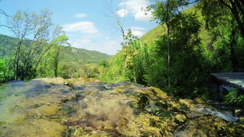 KRKA NATIONAL PARK, CROATIA - SEPTEMBER 5, 2021: Rocky water stream and view on the green hills in Krka National Park, Croatia. 4K, Ultra-wide, Audio