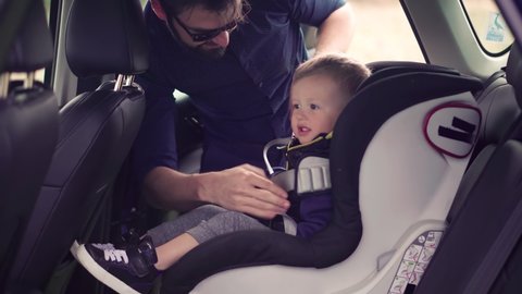 Happy Family Father And Child Boys Leisure. Father Fasten Son In Car Seat. Carefree Dad Baby Seat Sons Auto Trip Adventure. Family Parent Holidays Relationship. Car Baby Seat With Safety Seatbelt Trip