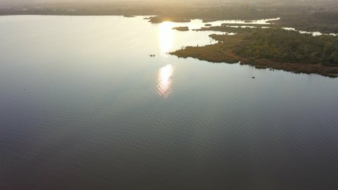 Aerial Panning Low And Tilting Up Over Serene Rawal Lake With An Early Morning Sun Low On The Horizon - Islamabad, Pakistan