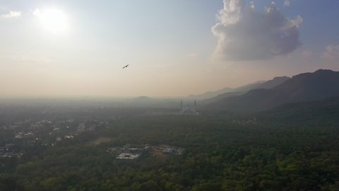 Aerial Reversing Away From The Faisal Mosque And Rolling Green Hills On A Hazy Morning - Islamabad, Pakistan