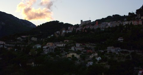 Aerial Forward Shot Of Flag On Fortress In Town On Mountain During Sunset - Monaco