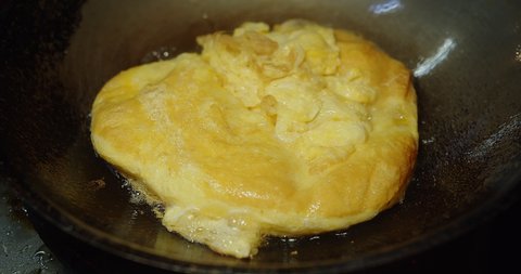 Close up cooking deep fried omelet egg in hot oil pan wok at the kitchen, simple street food in Thailand