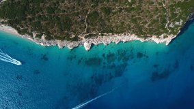 Bird eye view drone shot of Albanian coast in the Mediterranean sea - drone is descending, watching a speed boat. Snippet could ideally be used for travel or nature related videos or Albania movies.