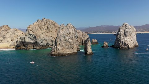 Drone shot of Playa del Amor and El Arco natural sea cliffs with boats in the ocean in Cabo San Lucas Mexico, wide and rotating