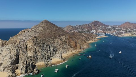 Drone shot starting on boats then revealing the mountains and beaches of Cabo San Lucas Mexico
