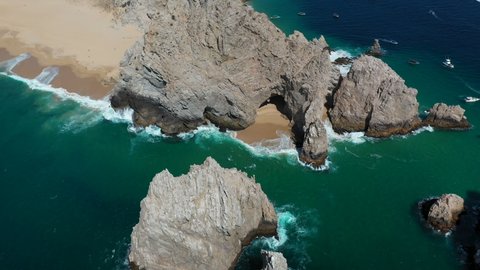 Cinematic drone shot of waves crashing on sea cliffs with Playa del Amor and El Arco in view in Cabo San Lucas Mexico
