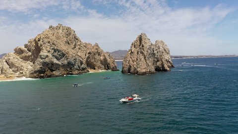 Aerial shot of boats in the ocean with sea cliffs in the background in Cabo San Lucas Mexico