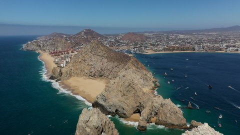 Drone shot of resorts on Playa El Médano then revealing Playa del Amor, Lover's Beach, and El Arco, a natural archway in the sea cliffs in Cabo San Lucas Mexico, wide and rotating