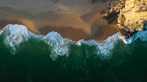 Cinematic downward angle drone shot of the waves and beautiful beaches in Cabo San Lucas Mexico