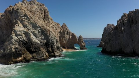 Cinematic drone shot of El Arco then revealing boats and mountains in Cabo San Lucas Mexico