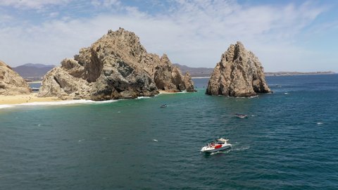 Drone shot of boats in the ocean with sea cliffs in the background in Cabo San Lucas Mexico