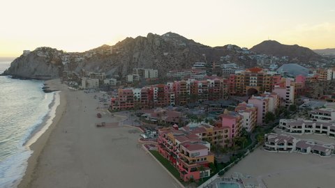 Drone shot of resort hotel on Playa El Médano with mountains in the distance in Cabo San Lucas Mexico, wide and rotating