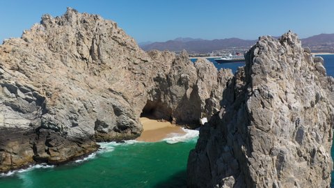 Drone shot of El Arco and sea cliffs and people in boats in Cabo San Lucas Mexico, rotating