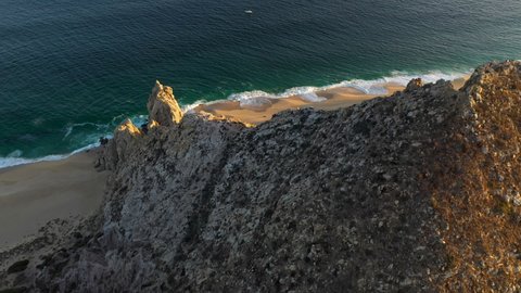 Drone shot coming over a mountain revealing the beach at Cabo San Lucas Mexico