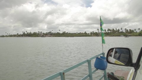 Jericoacoara - Ceara - 03-21-2022 Boat on a ferry crossing the river with the Brazilian flag flying in the wind waving the Brazilian flag. Brazil concept.