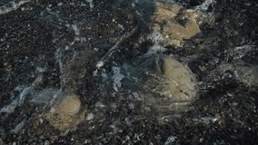 Sea waves are beating against the rocks on the coastline. Video with dark blue ocean water and foam waves. Slow motion video