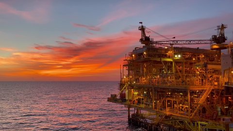 offshore oil and gas platform in sunset time the platform produced raw gases and crude oil for sent to onshore refinery, petrochemical plant and tanker for export for industry concept.