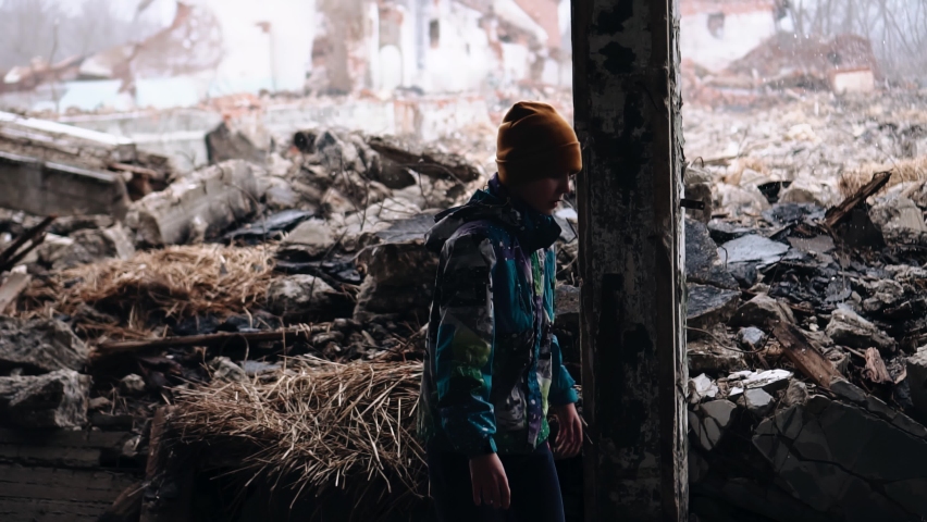 A teenager walks through the ruins of a destroyed building. Shooting in motion from the side Royalty-Free Stock Footage #1090093137
