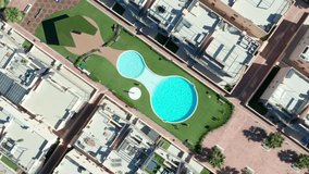 Pool overhead drone shot of kids jumping into blue turquoise water. Summer sunny vacation fun at hotel resort. Top down view family holidays theme