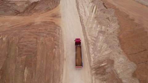 Sand transport in open pit. Dump truck transports sand and gravel in open-pit mine, drone view. Bulk Transport for construction. Earthmoving in quarry. Truck with tipper semi trailer in opencast. 
