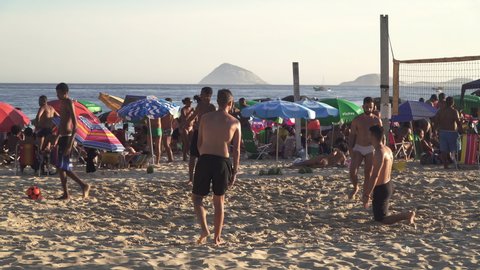 RIO DE JANEIRO, BRAZIL - FEBRUARY 2022: Group of young men play football at the Copacabana beach in Rio de Janeiro.
