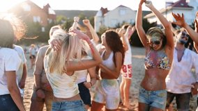 Cheerful girl celebrates Holi festival with friends stained in colored powder. People have fun at hindu holiday. Guys dance, jump on beach in slow motion. End of covid pandemic isolation - Powered by Shutterstock - Get 15% off with code: PIKWIZARD15