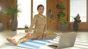 STILL SHOT: Female Asian yoga instructor describing pose at online yoga training. Philippine woman showing and explaining seated forward fold posture while running an online live video yoga course.