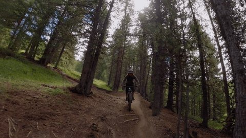 Mountain biker riding down a pathway in the forest. Rider point of view, mountain biking on high mountain terrain 