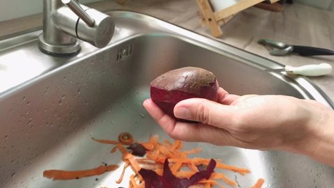 A woman cleans beets, hands close-up. The cook is peeling beets to make soup or another dish. High quality 4k footage