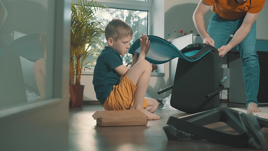 Father and son at home, active homeowners assembling furniture chair for the child. Cute Emotion of family.