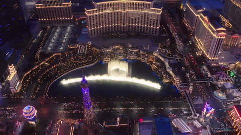 Aerial 4K high angle view of Strip cityscape with epic beautiful colorful night city lights view. Scenic Bellagio fountains show illuminated at night. Resort Casinos on Las Vegas Strip, USA Apr 2022