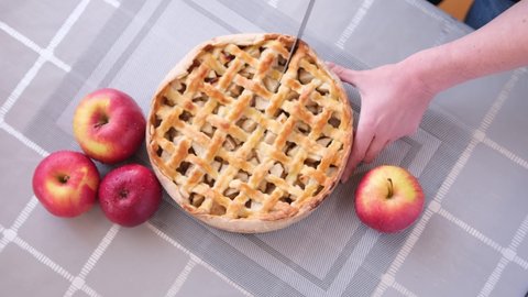 Apple pice cake preparation series - woman slicing pie on a table - top view