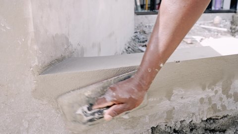 Manual Worker's Hand Plastering Wall Using Hand Trowel At Construction Site. close up, slow motion