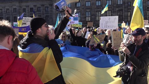 AMSTERDAM, NETHERLANDS – FEBRUARY 27 2022: Ukrainian man with loudspeaker chants slogan 'stop Putin, stop war', during solidarity protest against Russian invasion of Ukraine in Amsterdam. 