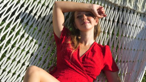 Peaceful attractive young woman relaxing in a hammock on vacation. Healthy calm girl relaxing on a comfortable outdoor swinging hammock, dream, stress-free, relaxing on vacation, dreaming of good