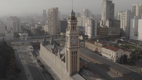 Aerial footage of train station with clock tower surrounded by buildings of downtown Sao Paulo, Brazil